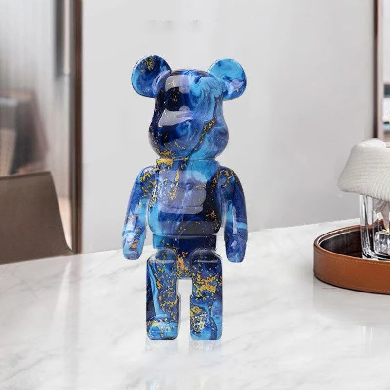 Blue and transparent graffiti bear figurine on a white surface with a blurred background