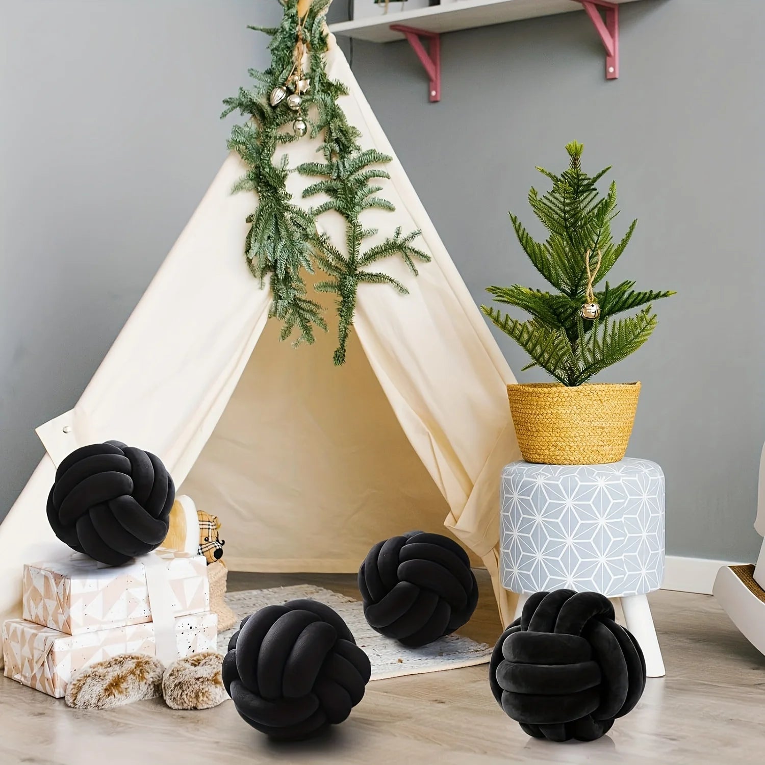 Children's play area with a teepee, black knot pillows, and decorative plants.