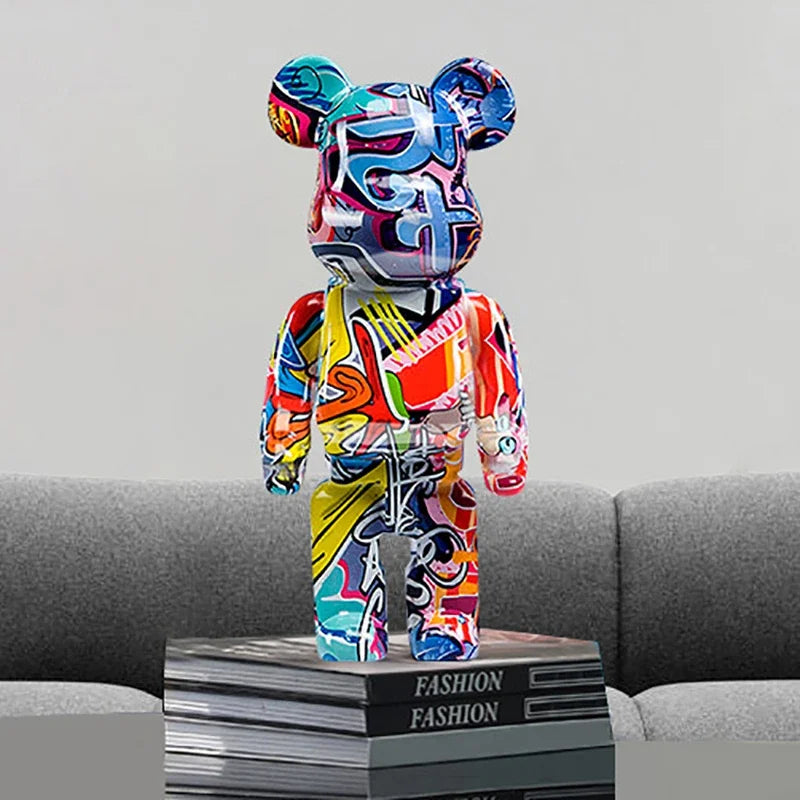 Colorful graffiti bear figurine on a stack of books with a gray couch background