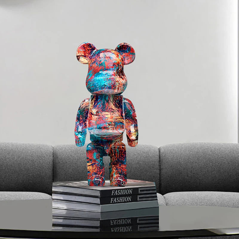 Colorful graffiti bear figurine on a stack of books with a gray sofa in the background