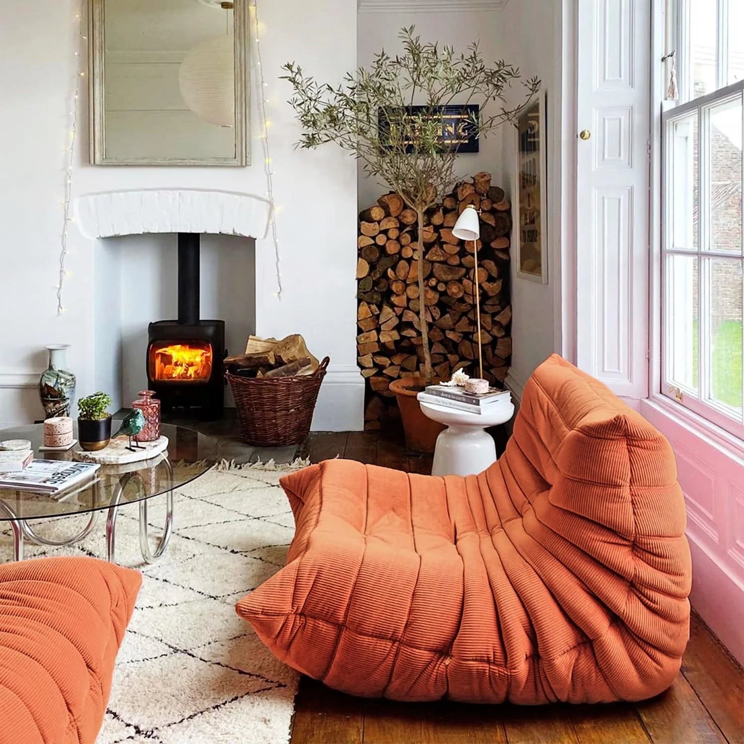 Cozy living room with Orange Corduroy Caterpillar Lazy Sofa, fireplace, and wooden logs.
