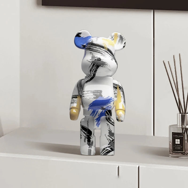 Decorative graffiti bear figurine with abstract design on a shelf next to a diffuser.