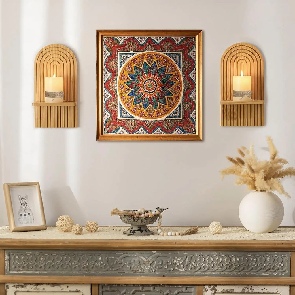 Decorative wall art with candles and a vase on a table against a light gray wall.