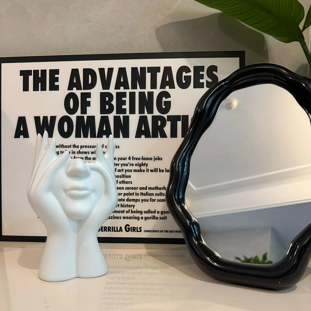 Nordic Human Body Sculpture Desk Organizer, black mirror, and framed text on a surface.