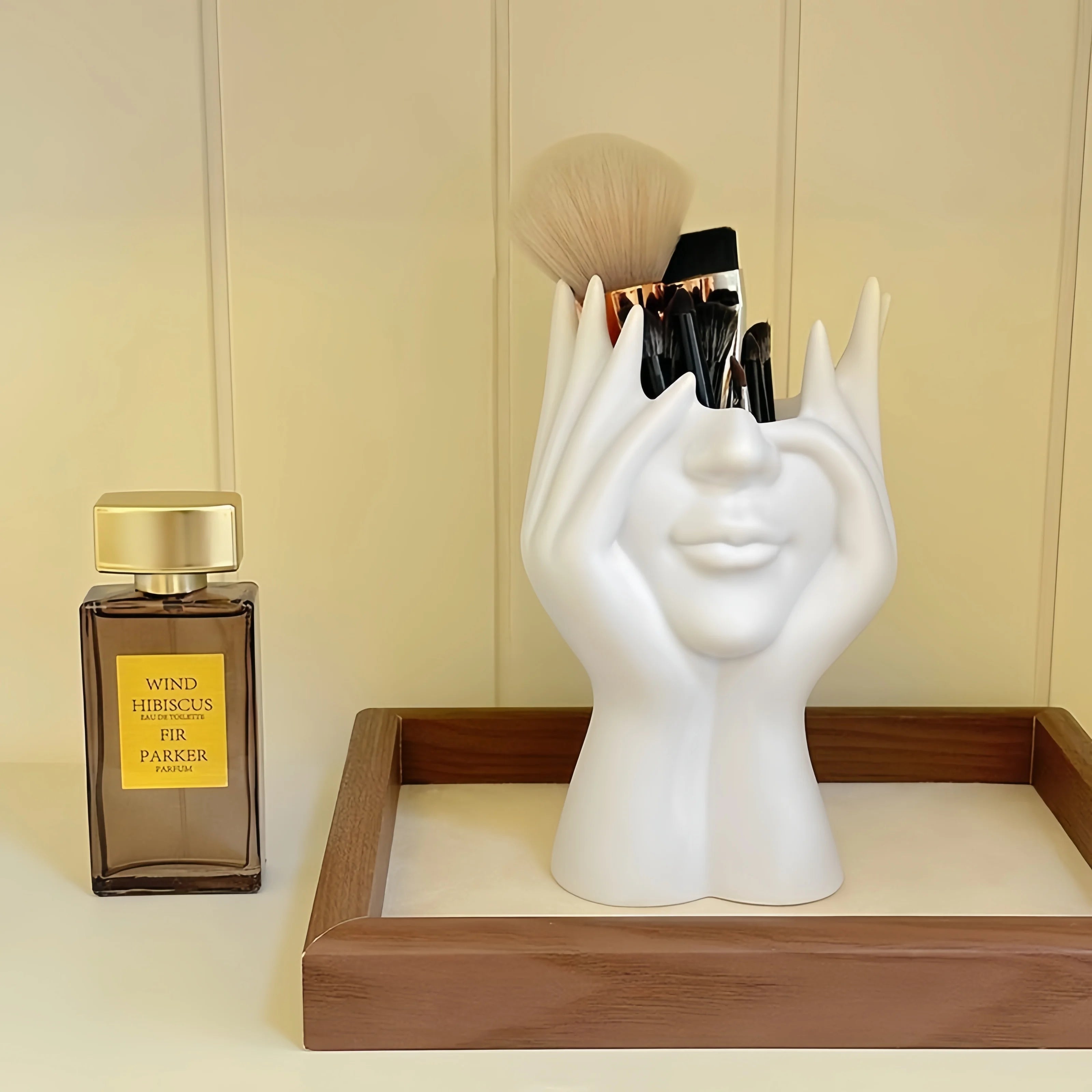 Nordic Human Body Sculpture Desk Organizer with makeup items on a wooden tray next to a perfume bottle.