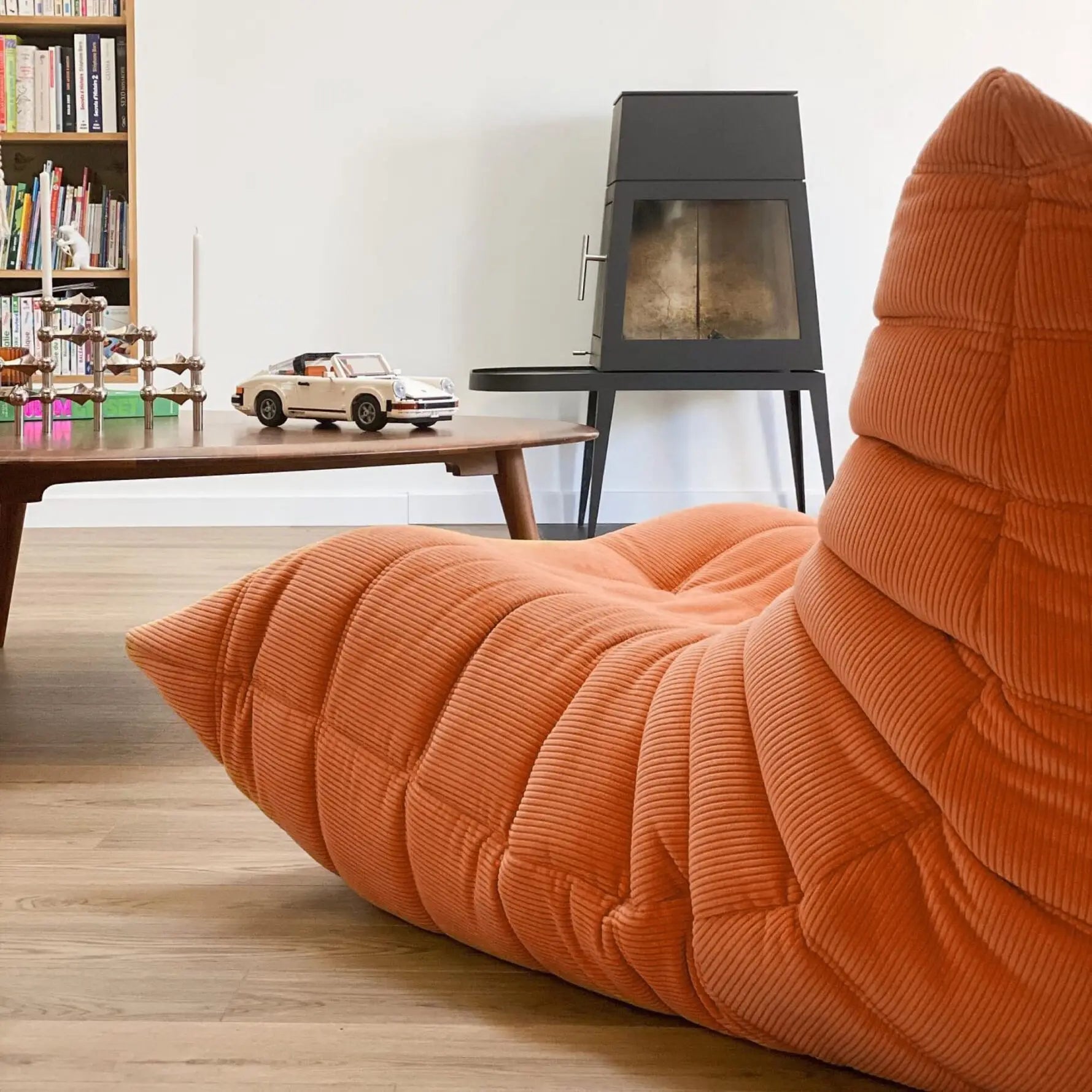 One seater Orange Corduroy Caterpillar Lazy Sofa in a living room with a fireplace and bookshelf.