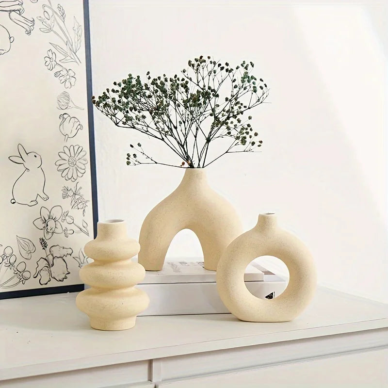 Set of three light yellow Boho Ceramic Vases on a white surface with a framed picture in the background.