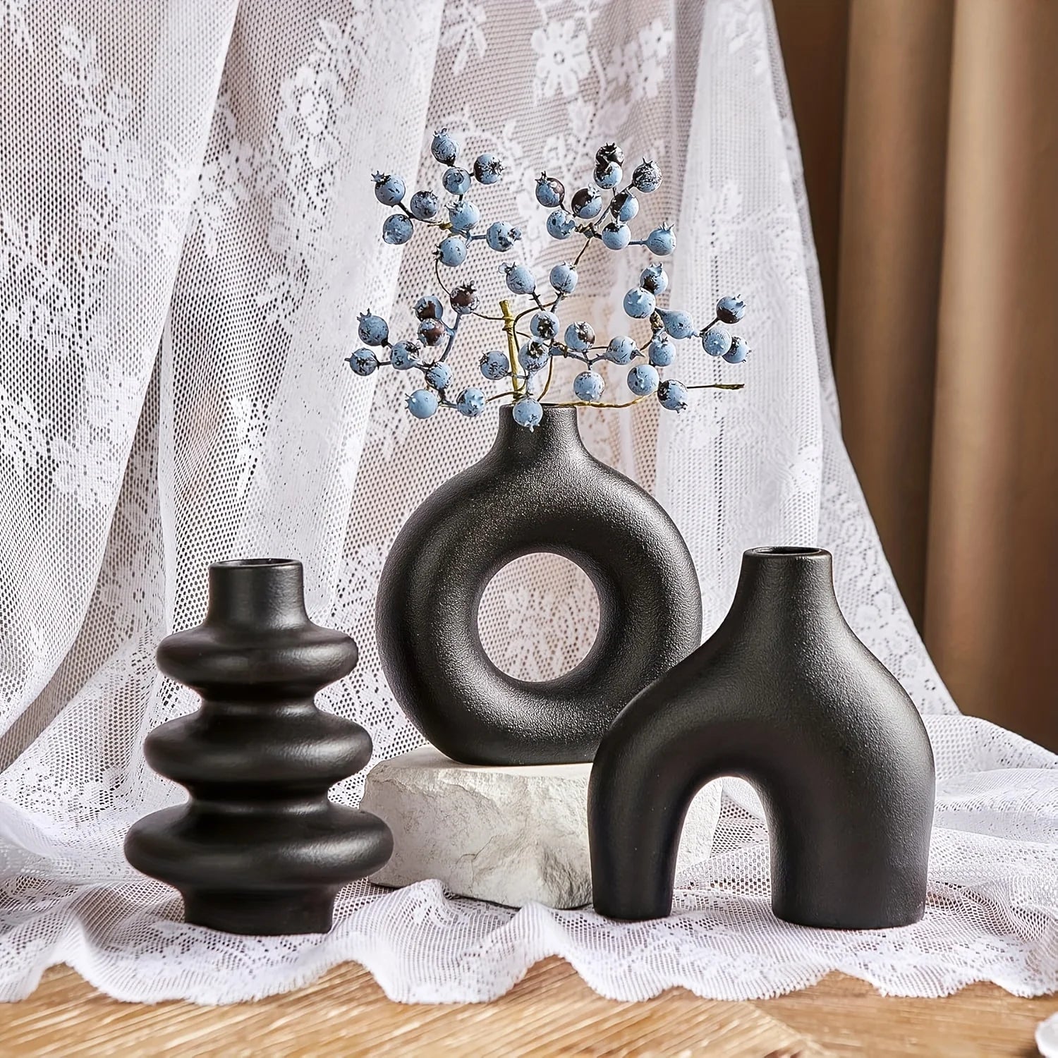 Three black Boho Ceramic Vases on a lace tablecloth with a blurred background