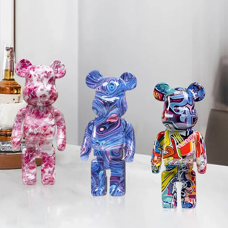 Three colorful graffiti bear figurines on a white surface with a neutral background