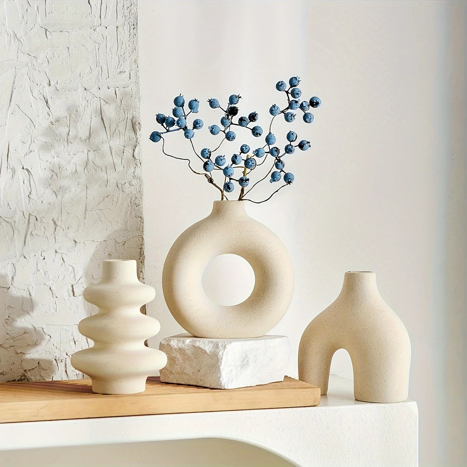 Three light yellow Boho Ceramic Vases on a wooden shelf with a textured wall background