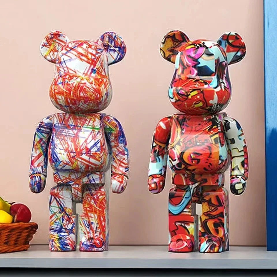 Two colorful, abstract-patterned graffiti bear figurines on a shelf with a neutral background.