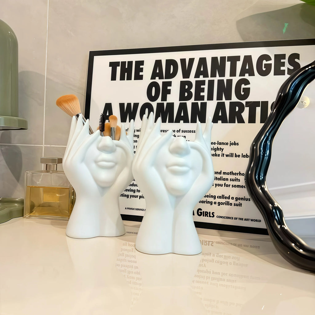 Two white Nordic Human Body Sculpture Desk Organizers on a surface with a poster in the background.