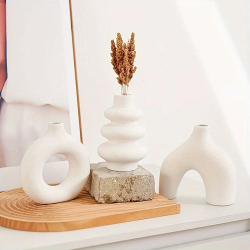White Boho Ceramic Vase with dried flowers on a wooden surface, surrounded by other decorative vases.