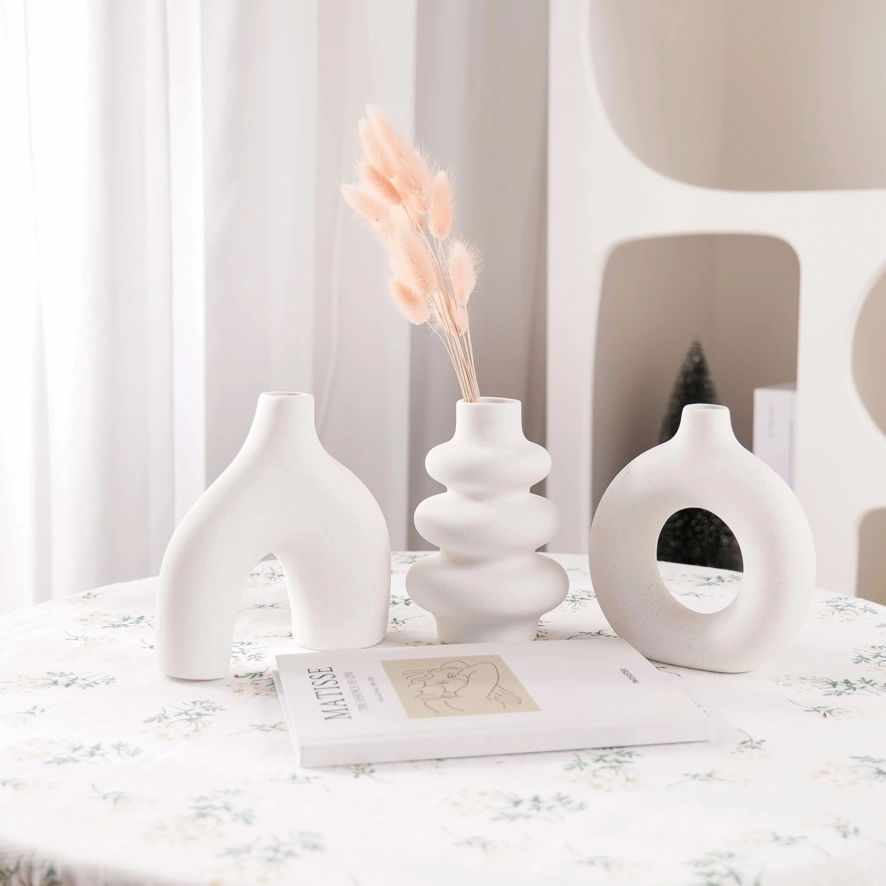 White Boho Ceramic Vases on a table with a lamp and decorative book in the background