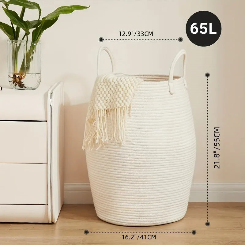 White woven Boho Cotton Rope Storage Basket with handles on a wooden floor, next to a white cabinet and plant, with measurements displayed.